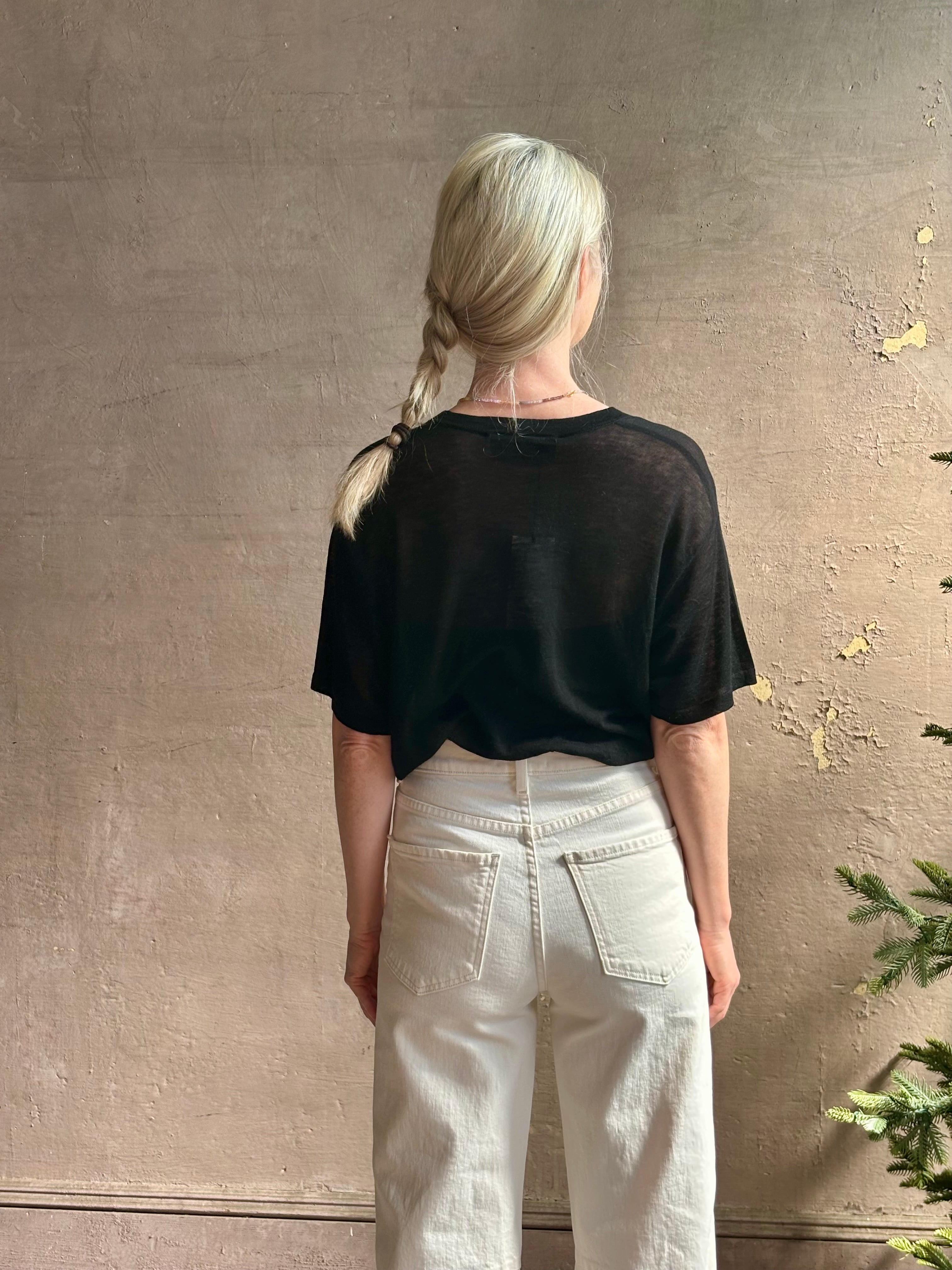 Mature woman wearing V Neck Tee from SPRWMN rendered in a timeless black and crafted from 100% premium sheer wool with fluid draping and short sleeve