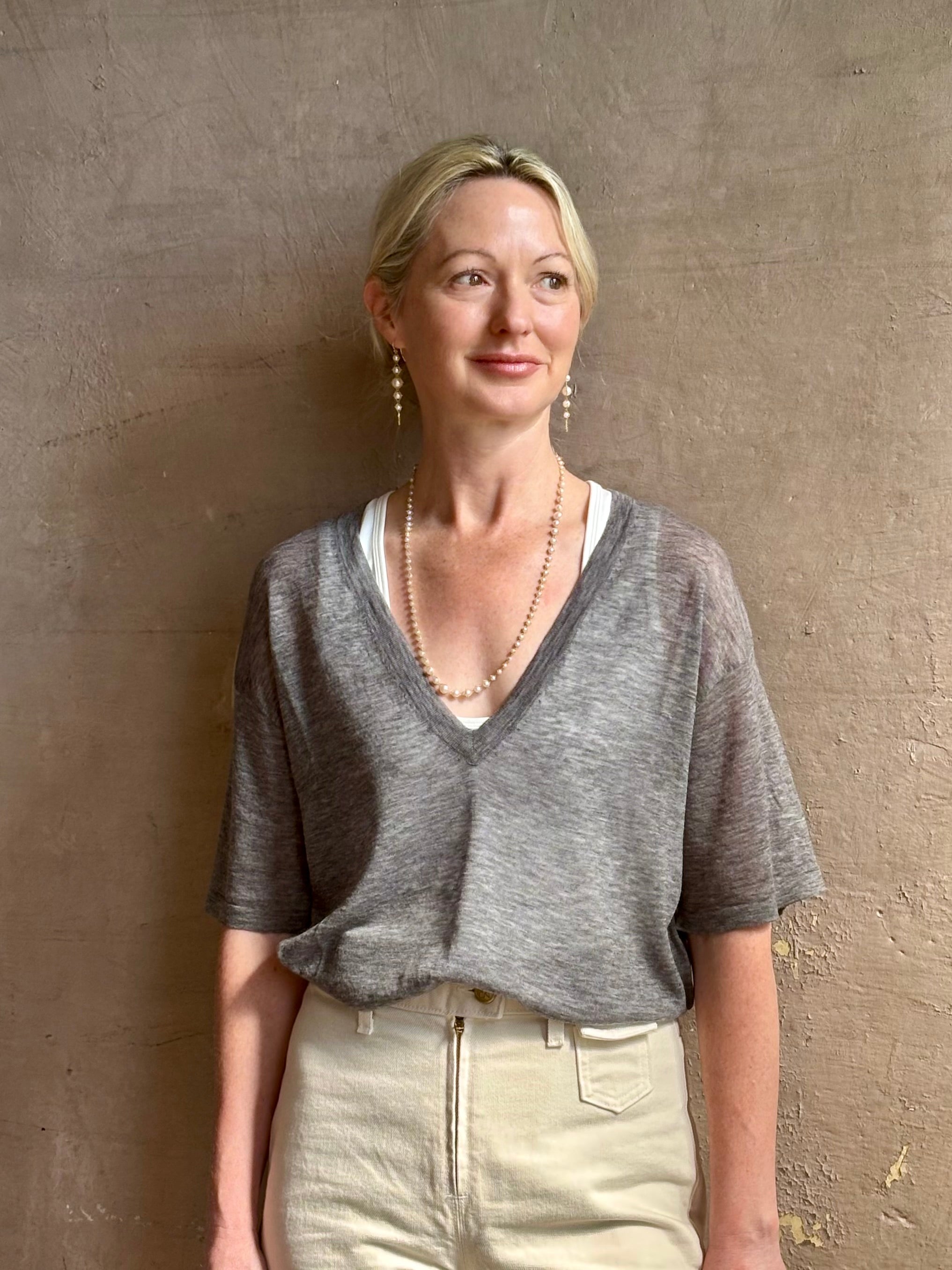Mature woman wearing premium polished layer SPRWMN grey wool tee shirt with a v-neck and short sleeves
