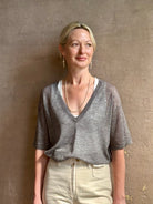 Mature woman wearing premium polished layer SPRWMN grey wool tee shirt with a v-neck and short sleeves
