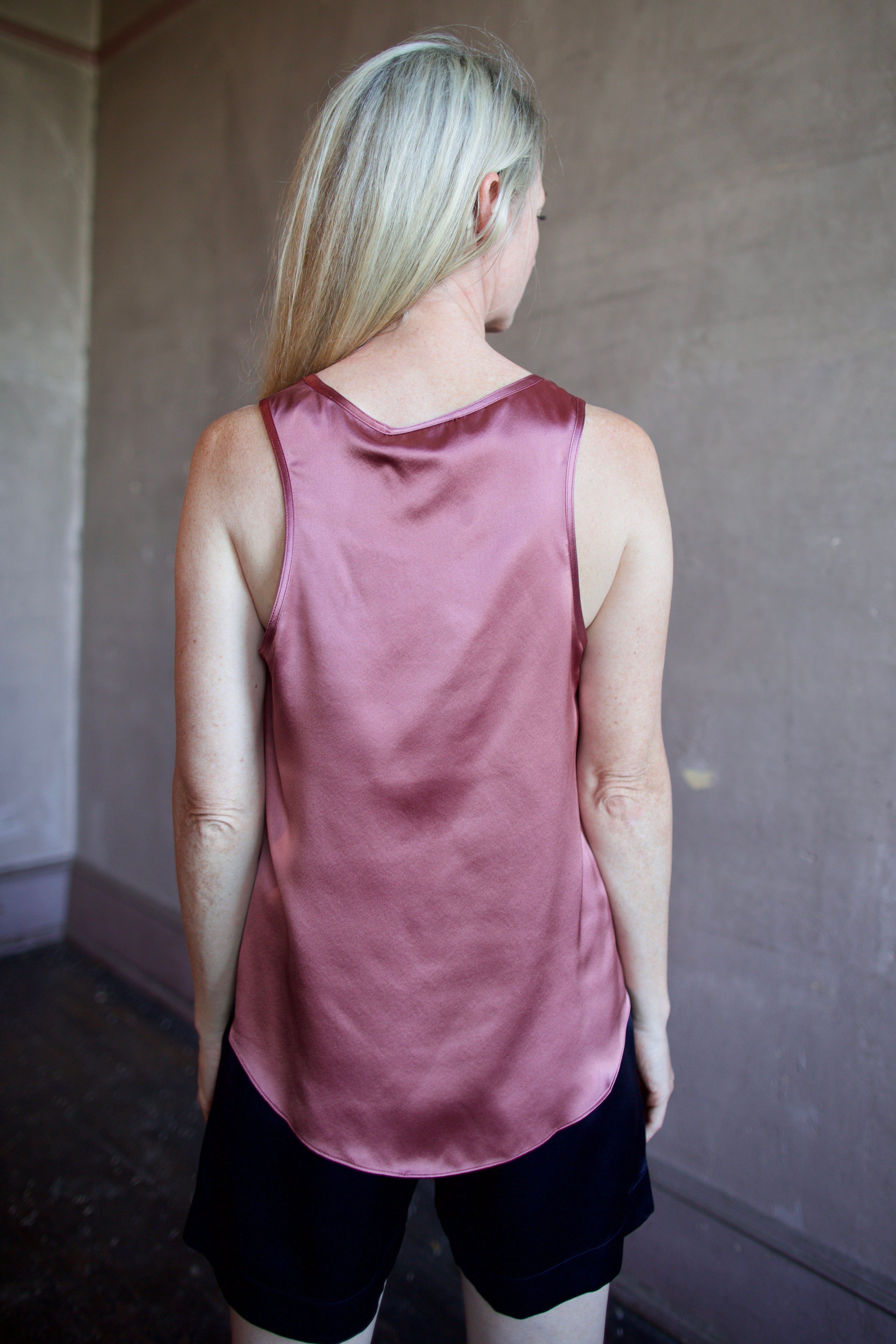 Image of a woman wearing luxury brand Sablyn Claudia B Scoop Neck silk charmeuse layering Tank in desert bloom mauve colorway
