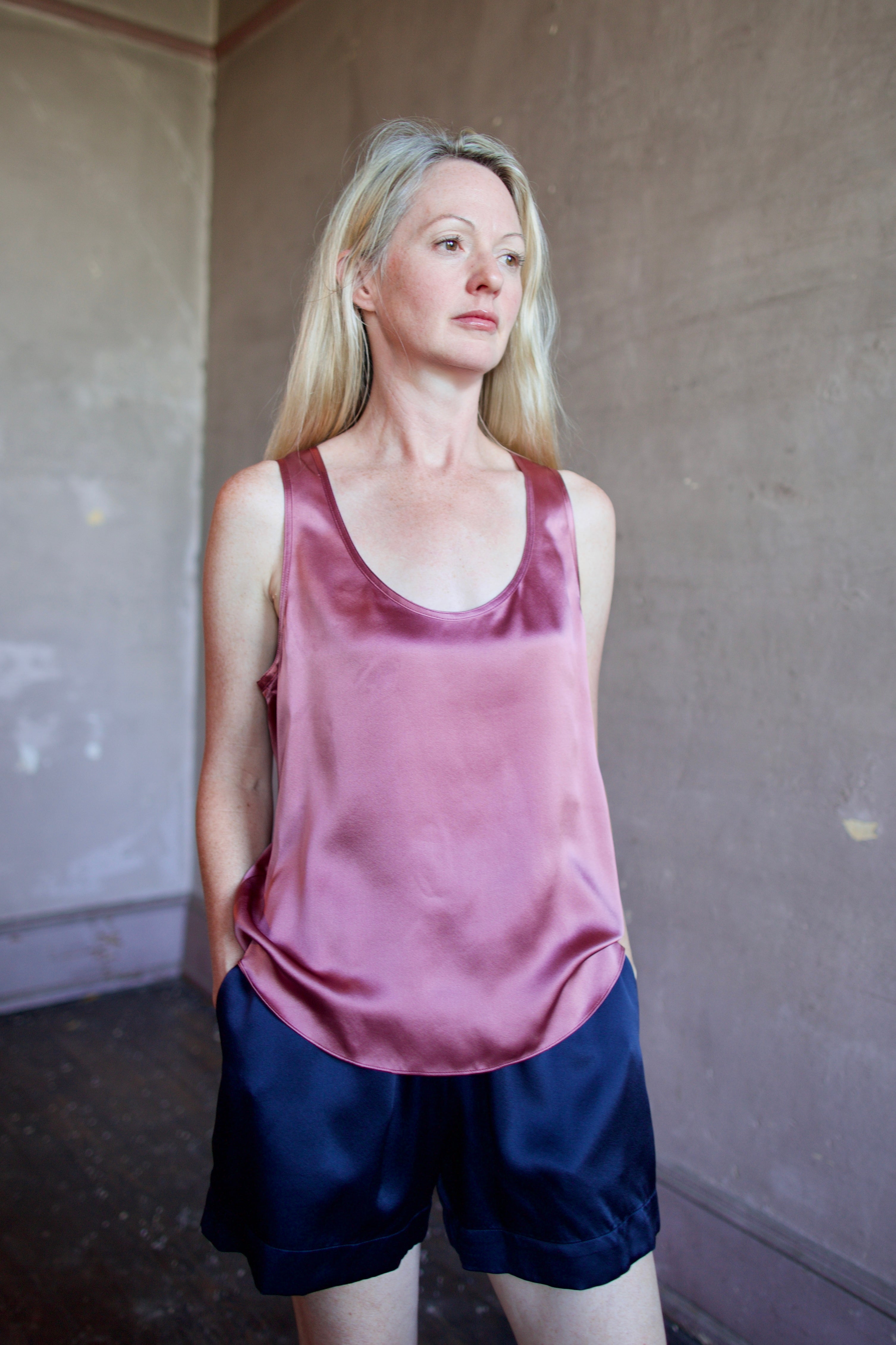 Image of a woman wearing luxury brand Sablyn Claudia B Scoop Neck silk charmeuse layering Tank in desert bloom mauve colorway