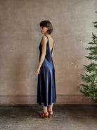 Womanl wearing luxury Sablyn navy blue silk charmeuse sleeveless slip maxi dress with scoop neck and low back 