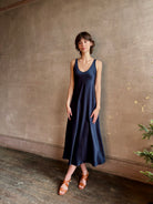 Womanl wearing luxury Sablyn navy blue silk charmeuse sleeveless slip maxi dress with scoop neck and low back 