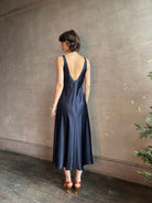 Womanl wearing luxury Sablyn navy blue silk charmeuse sleeveless slip maxi dress with scoop neck and low back 