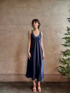 Womanl wearing luxury Sablyn navy blue silk charmeuse sleeveless slip maxi dress with scoop neck and low back 