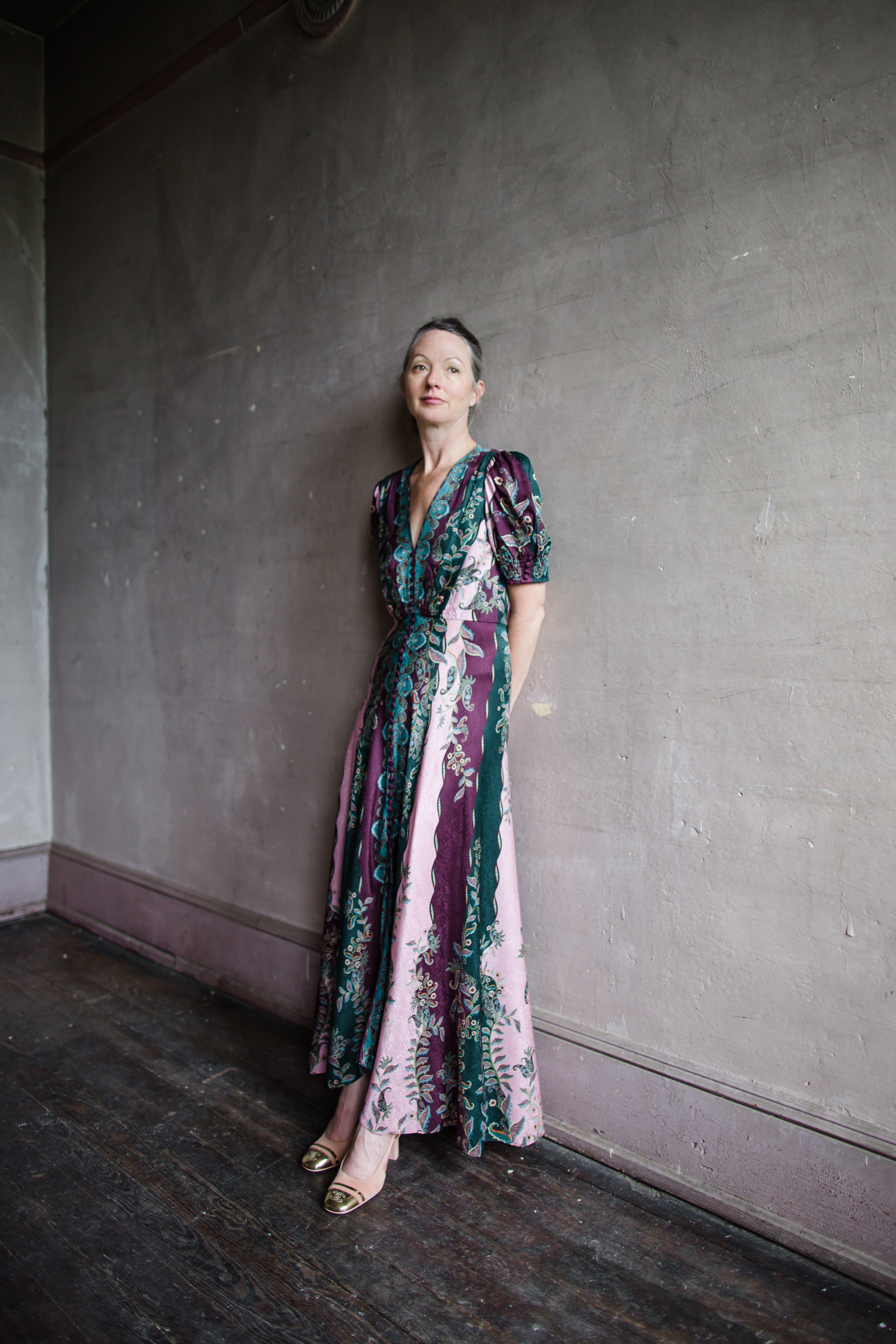 Image featuring a woman wearing the Lea Long silk Dress by Saloni with a v neckline, button front, puff short sleeves and a tailored waist in stripe plum, teal, & pink.