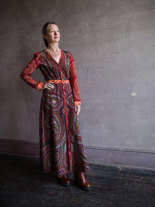 Image featuring a woman wearing the Lea silk dress by Saloni with a v neckline, button front, and removable belt in a red paisley print.