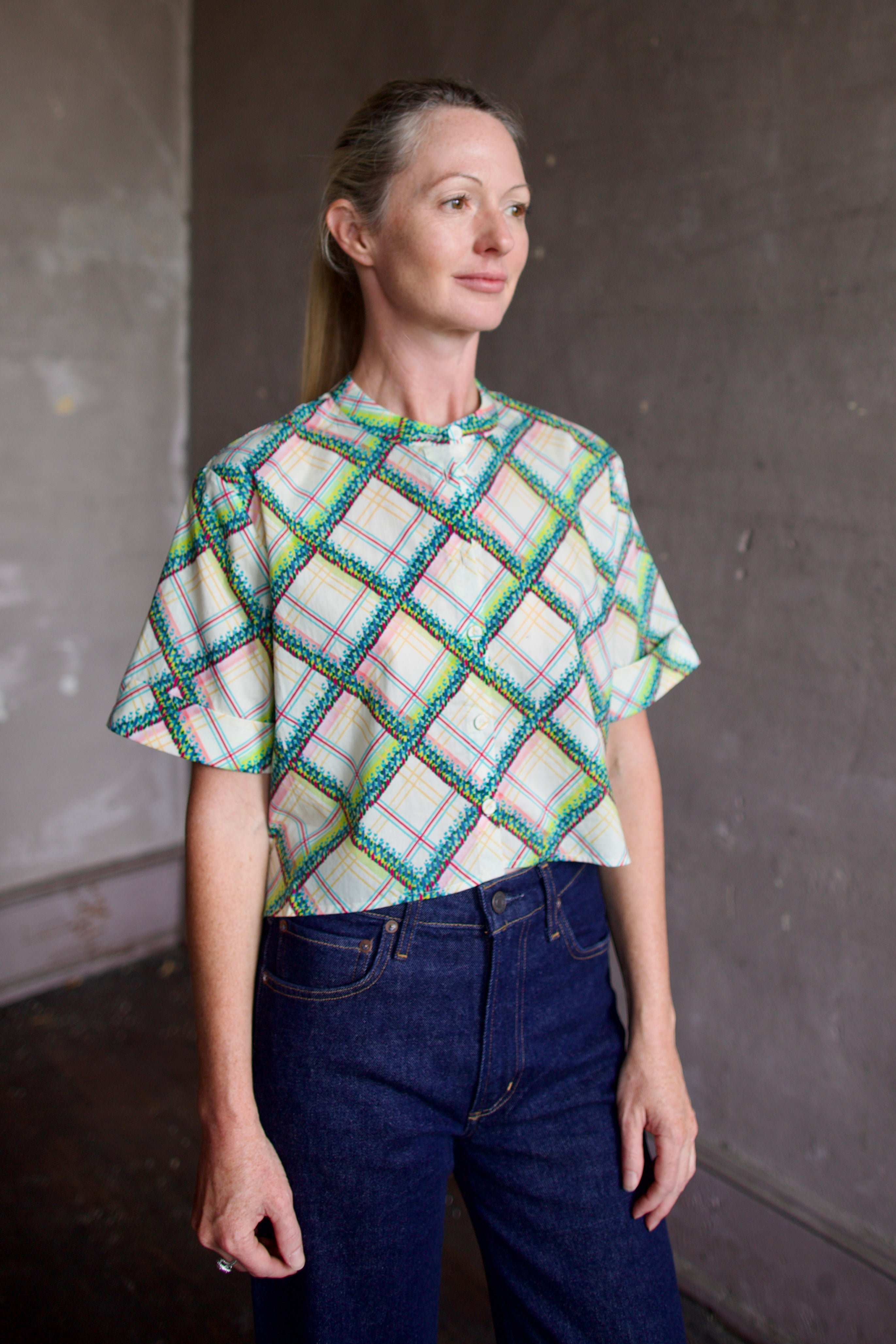 Model wearing the Saloni Jude short sleeve plaid button up crop top and AGOLDE dark denim