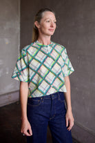 Model wearing the Saloni Jude short sleeve plaid button up crop top and AGOLDE dark denim