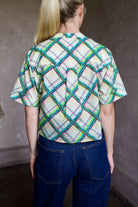 Model wearing the expertly tailored Saloni Jude short sleeve plaid button up crop top and AGOLDE dark denim