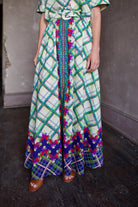 Model wearing Saloni Judi maxi plaid skirt, matching belt, and trimmed in pansies down front and around skirt bottom