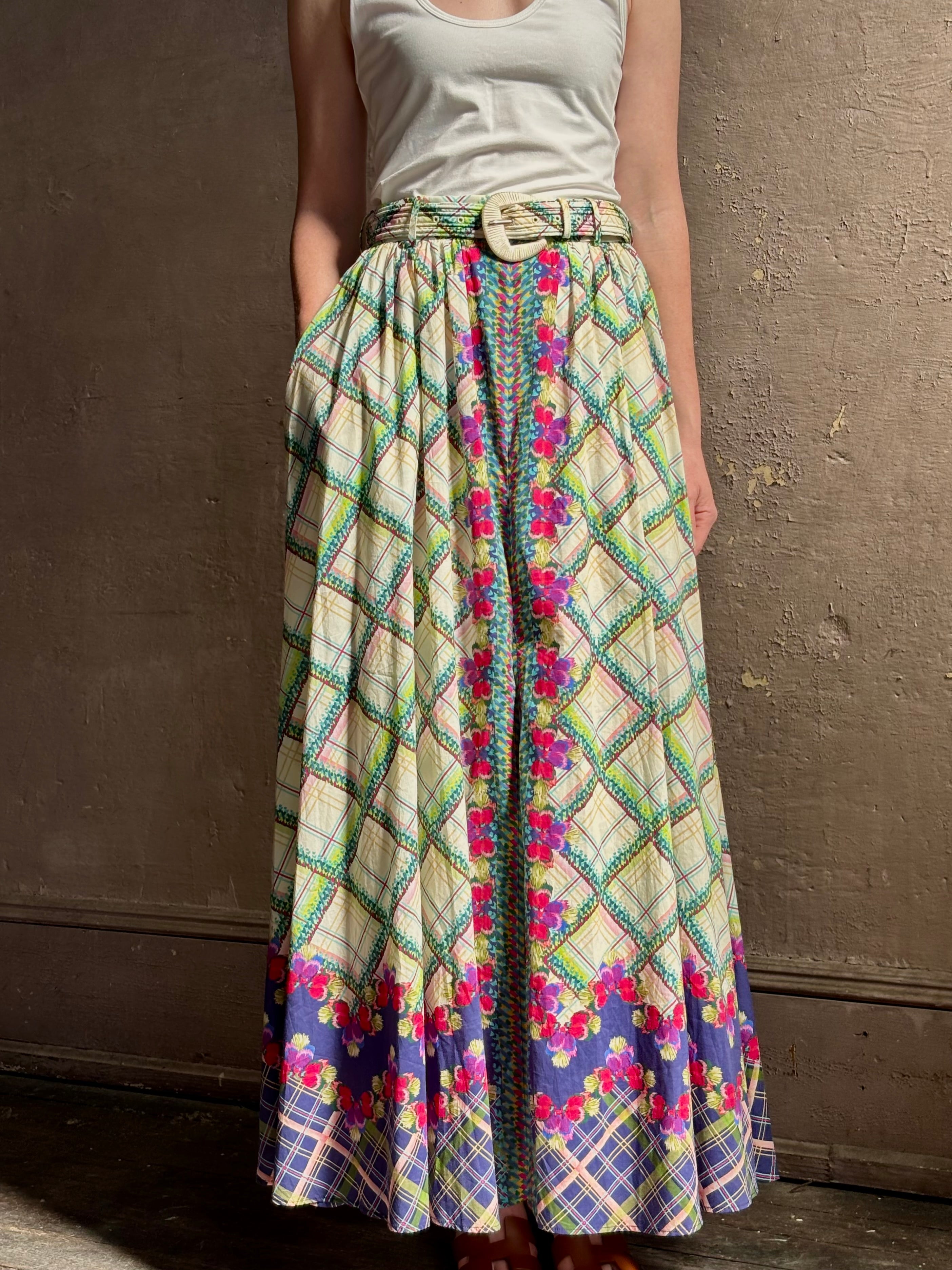 Mature woman reviewing Saloni Judi maxi plaid skirt with matching belt. This cotton A-line skirt is trimmed in pansies down front and bottom with front opening for additional ventilation
