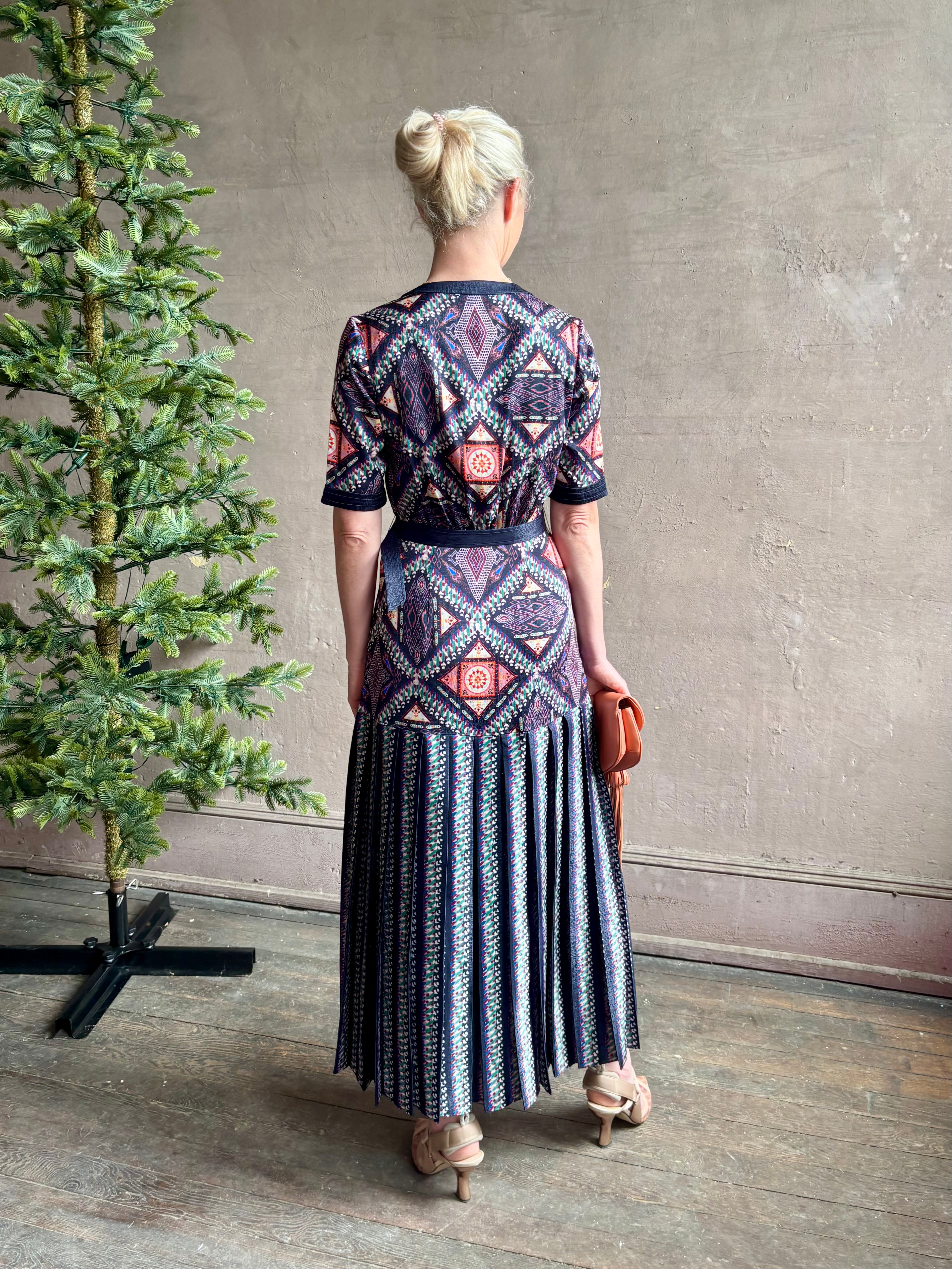 Mature woman wearing timeless Saloni Lea drop waist button front dress in ikat compass print and pleated skirt wit v-neck and short sleeves