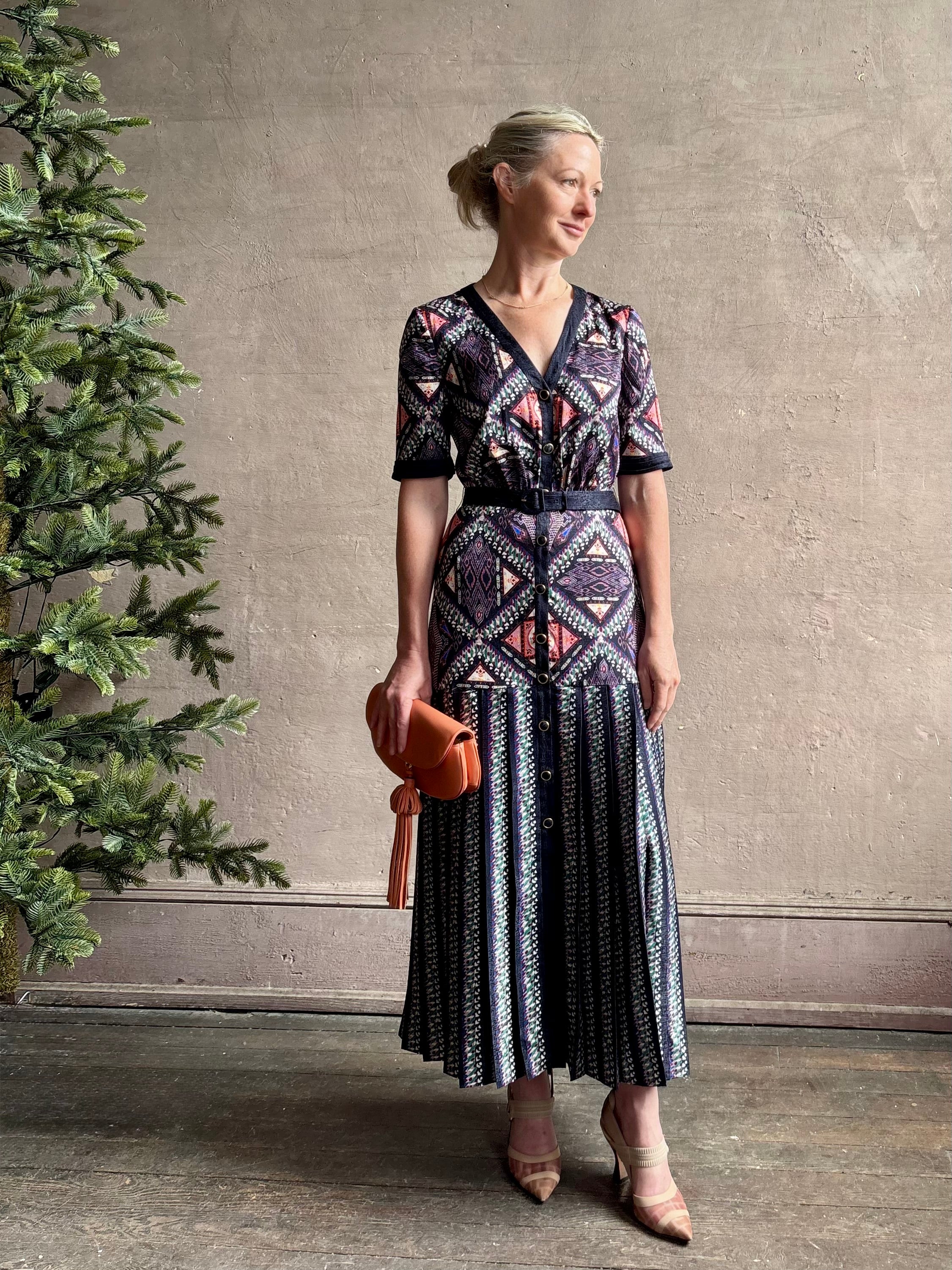Mature woman wearing timeless Saloni Lea drop waist button front dress in ikat compass print and pleated skirt wit v-neck and short sleeves