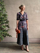 Mature woman wearing timeless Saloni Lea drop waist button front dress in ikat compass print and pleated skirt wit v-neck and short sleeves