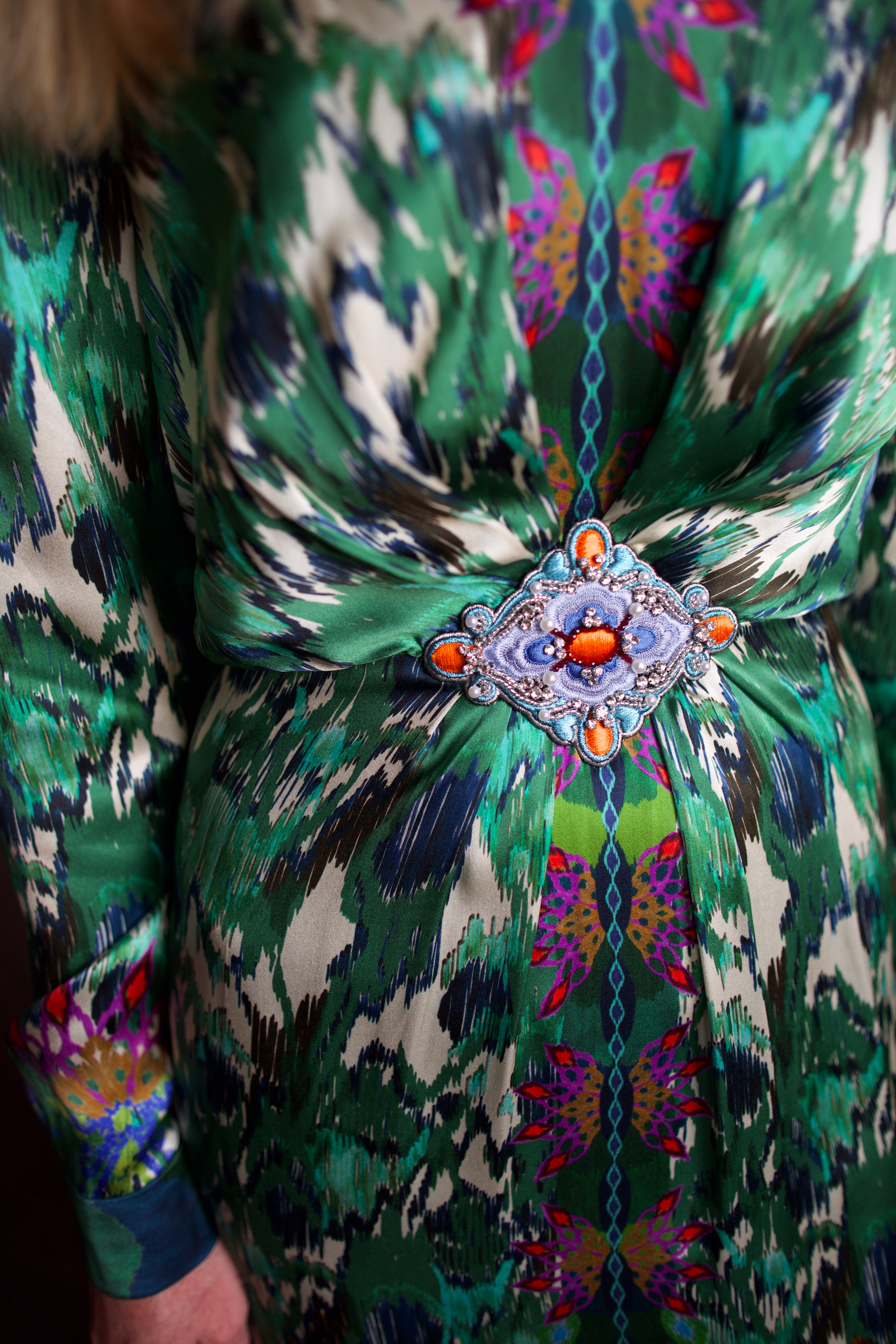 Model wearing Saloni Mya silk long sleeve green floral midi dress with embellished broach detail at waist