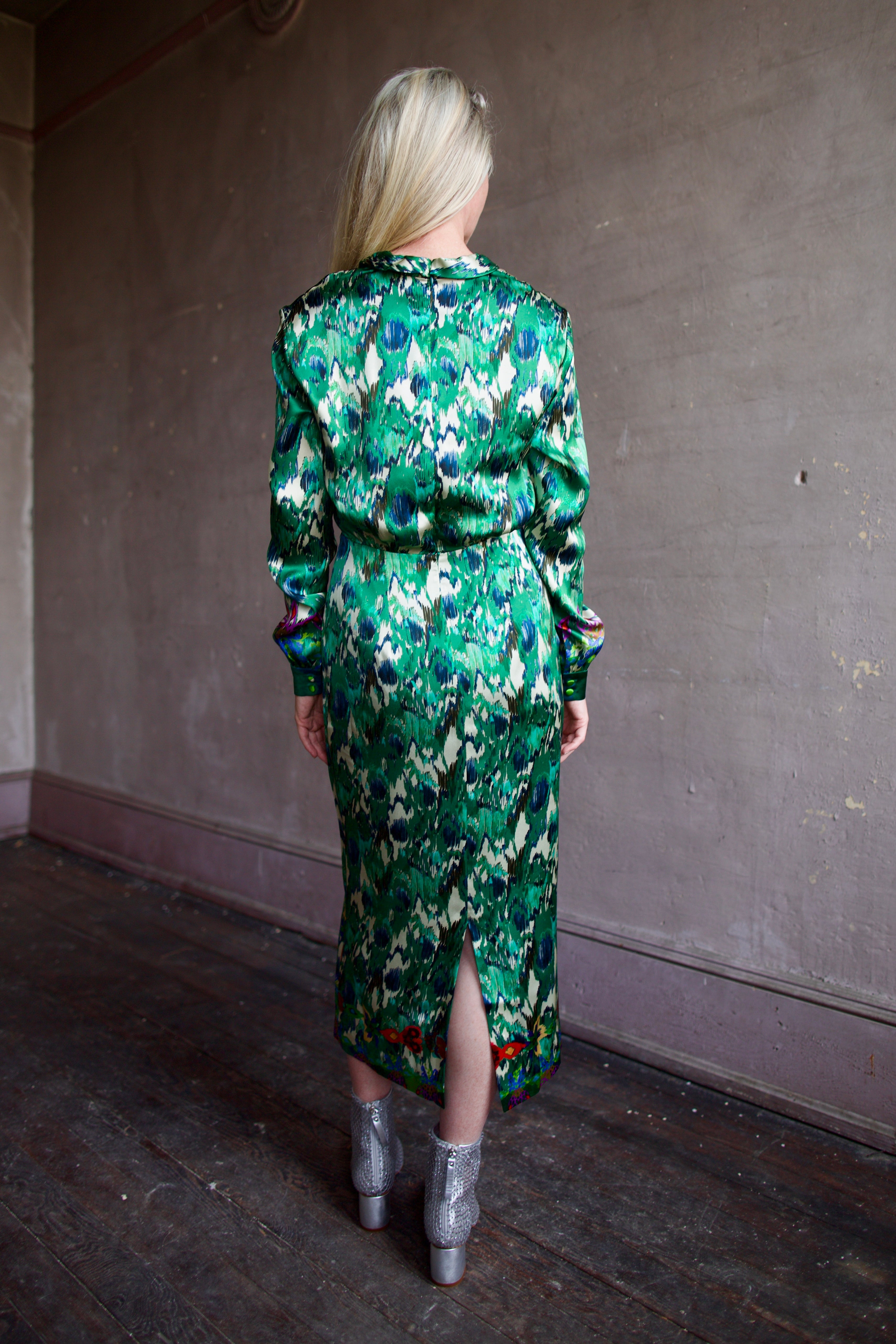 Mature woman wearing Saloni Mya silk long sleeve green floral midi dress with embellished broach detail at waist, long sleeves, and V-neck