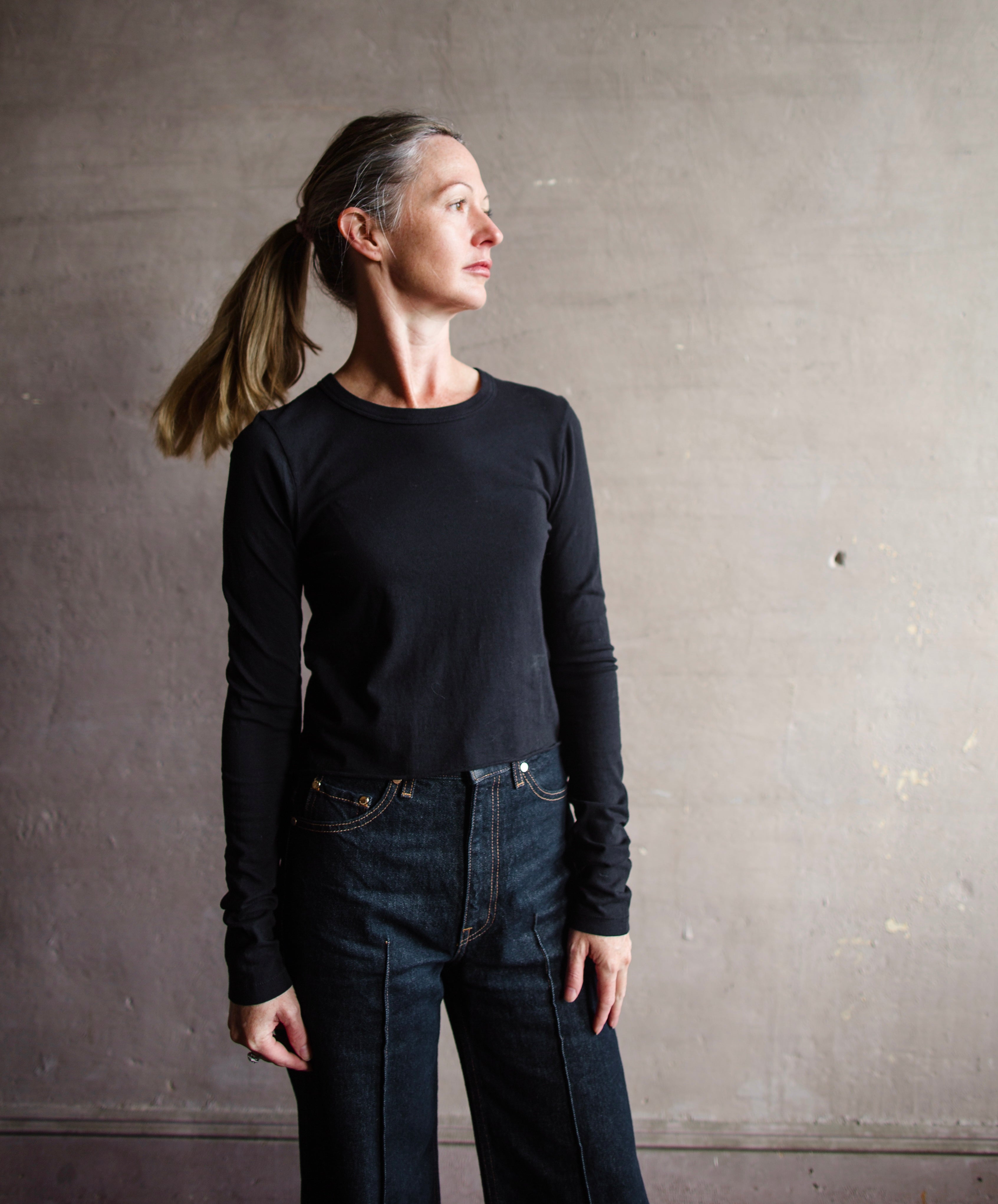 Image featuring a woman wearing the Slvrlake The Baby Long Sleeve Tee by Slvrlake baby tee with a crew neckline, long sleeves and a cropped fit fabricated in cotton.