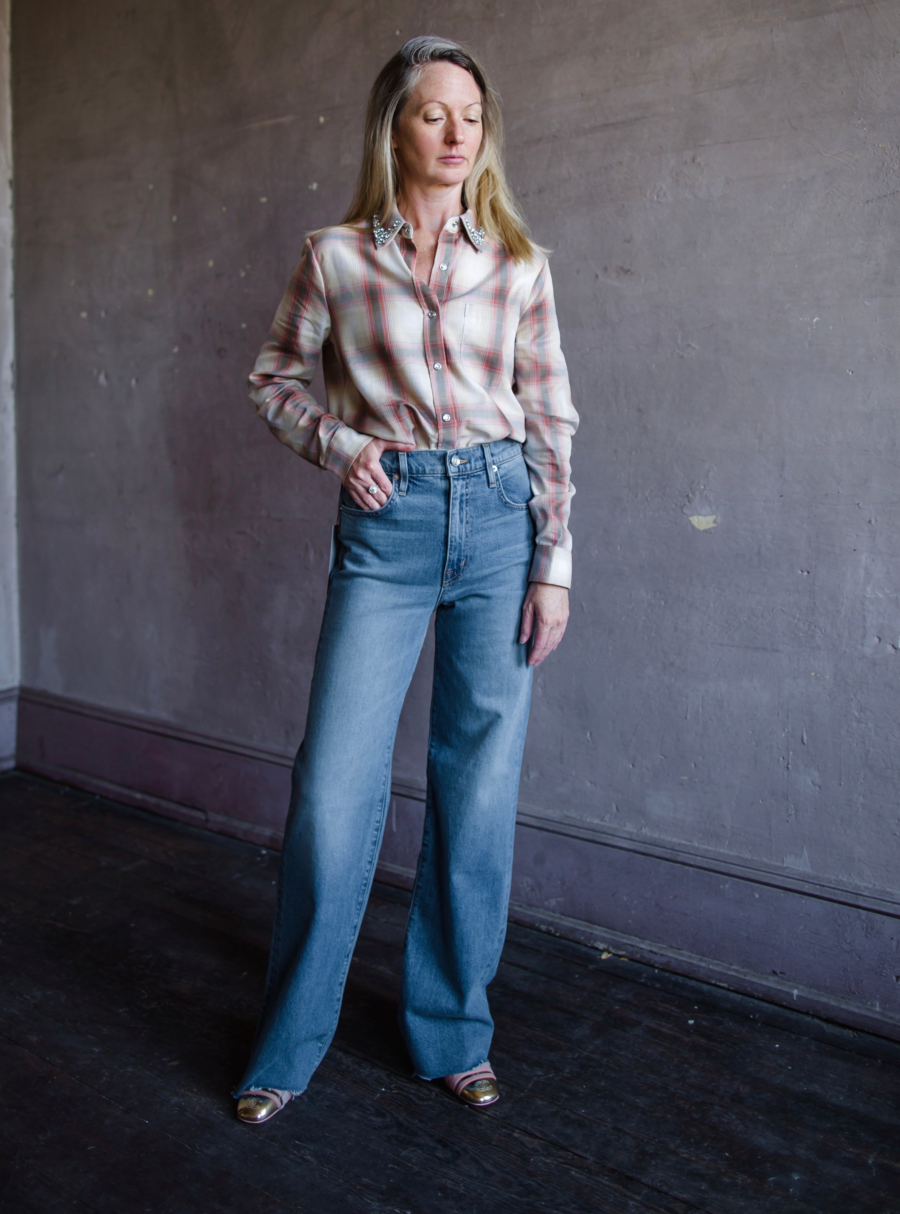 Mature woman wearing Slvrlake Grace denim jeans in 100% cotton rigid denim high rise full length wide leg medium wash