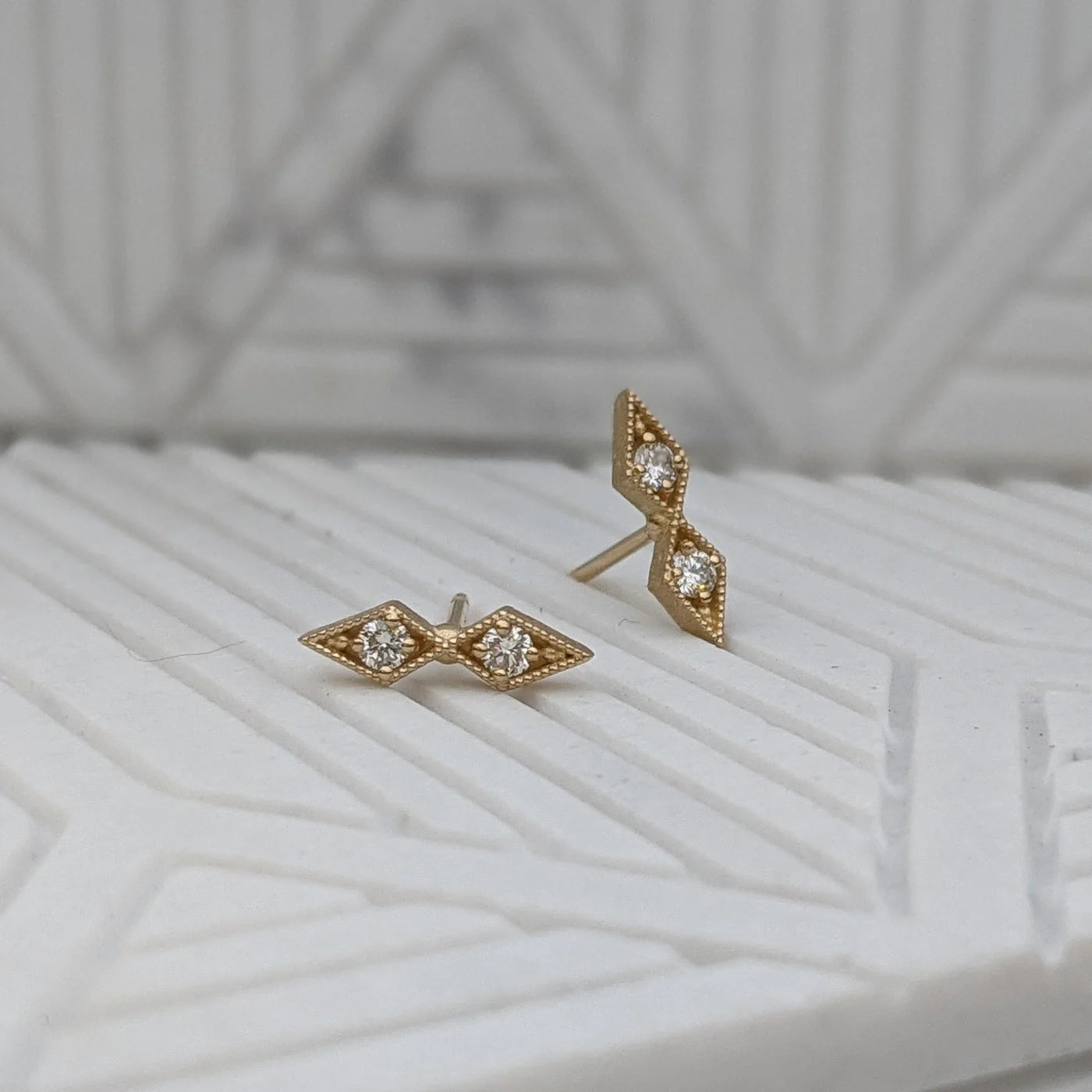 Image featuring North Carolina artist Stephanie Ellis’s diamond double star stud earrings in recycled 14-karat yellow gold with 4-2mm SI1-G white round brilliant diamonds. 