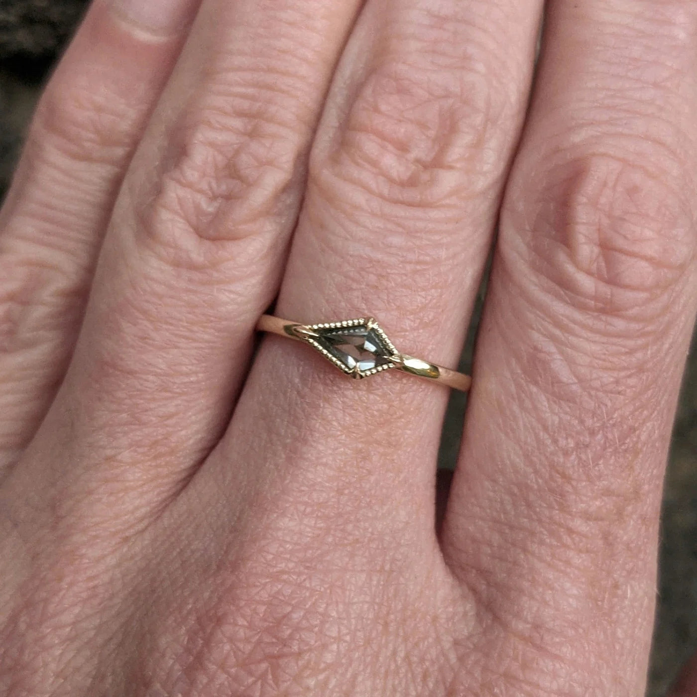 Image featuring a woman wearing  North Carolina artist Stephanie Ellis stacker ring in 14-karat recycled yellow gold, 0.40ct salt and pepper kite-shaped diamond.