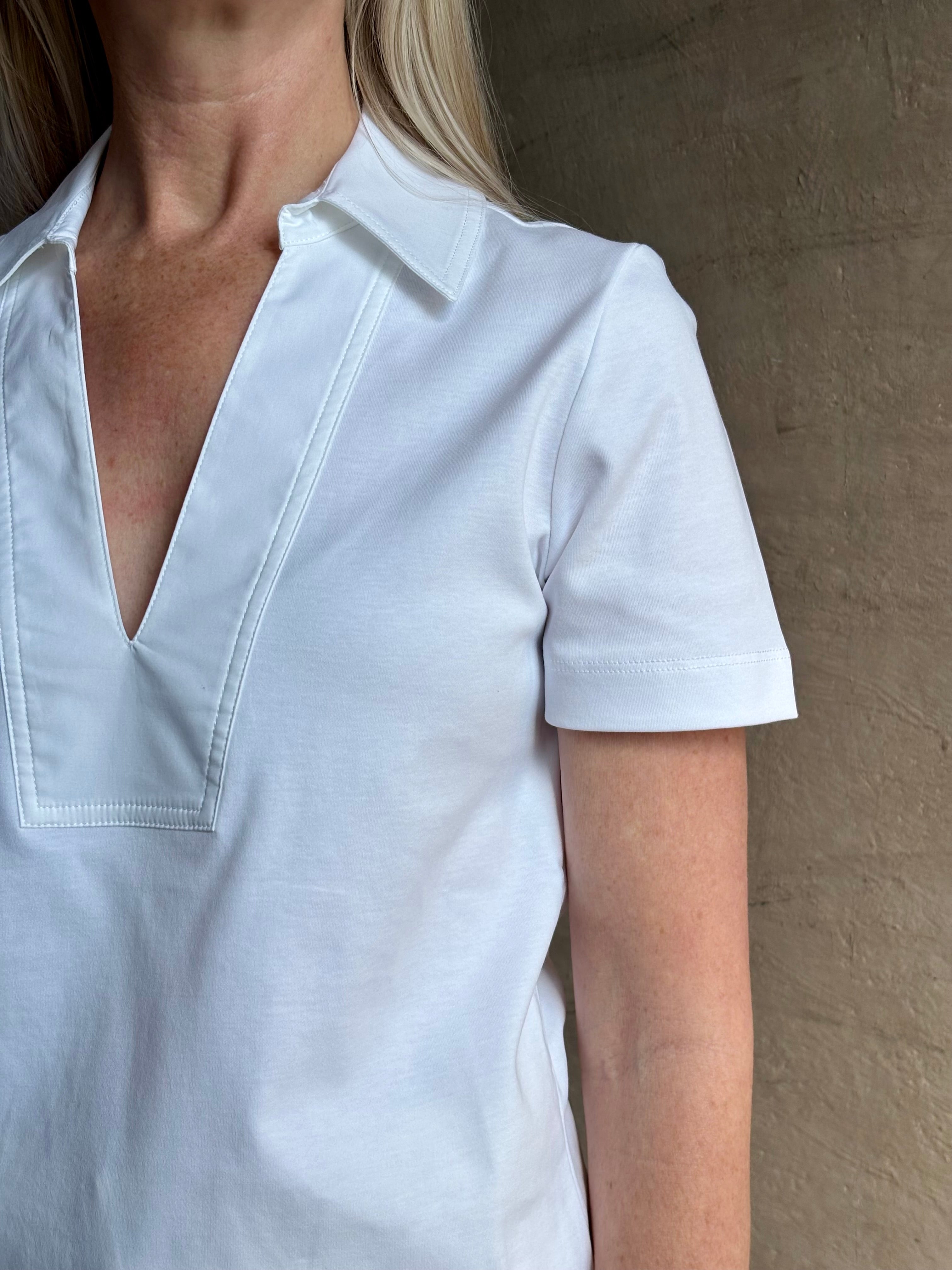 Mature woman wearing timeless white Melanie Top from Tanya Taylor crafted from 100% organic cotton jersey with v-neck and short sleeves in effortless relaxed fit for an elevated waredrobe staple