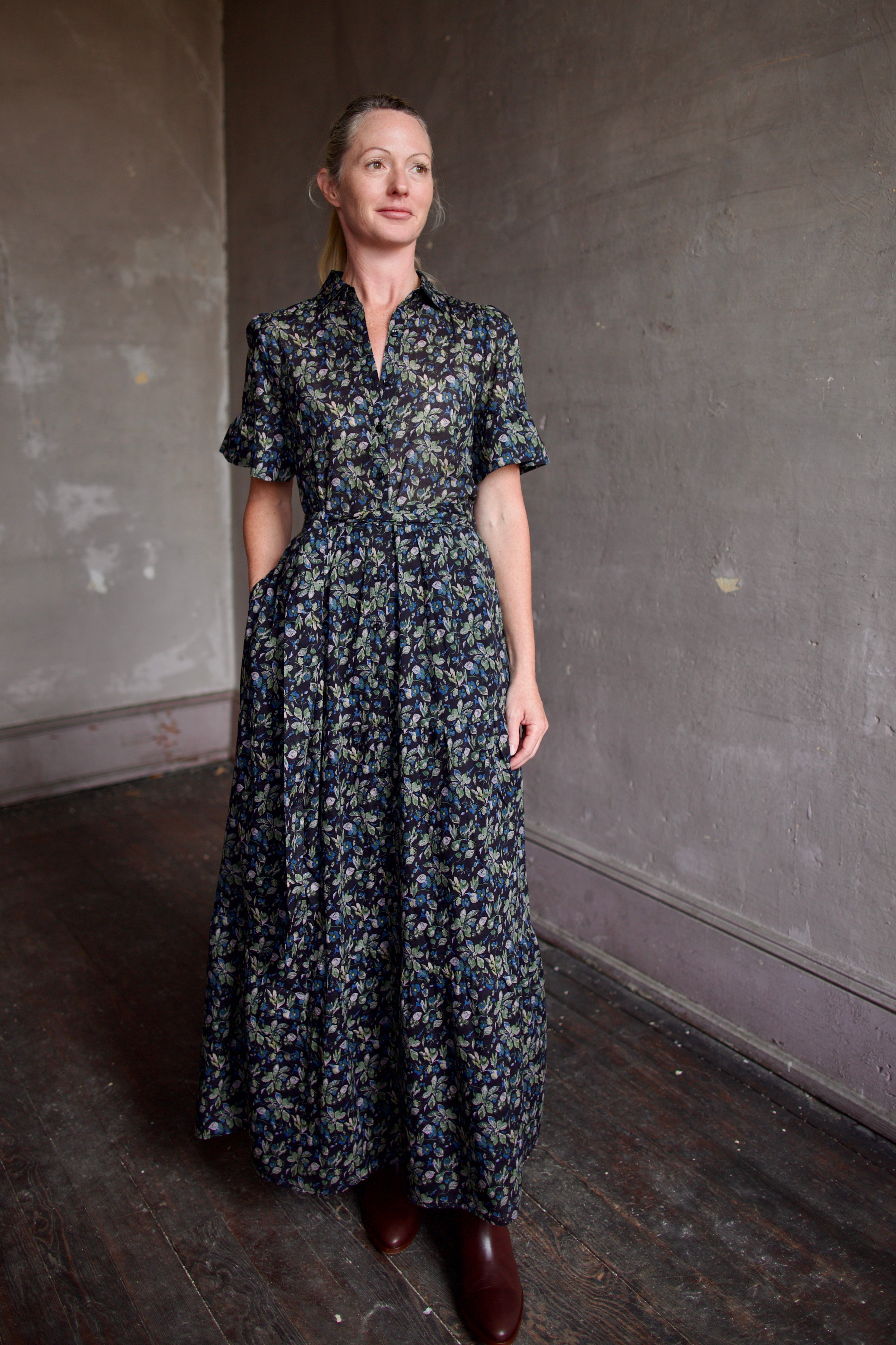 Image of model wearing Trovata Martine cotton dress in  a dark floral print with ruffle trim short sleeves