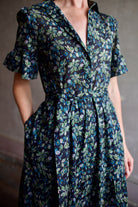 Image of model wearing Trovata Martine cotton dress in  a dark floral print with ruffle trim short sleeves