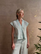 Mature woman wearing Dorada short sleeve Shirt from Trovata rendered in a fresh aqua and cream Stripe and crafted from  cotton poplin with v-neck, collar and consealed button front