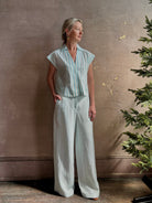 Mature woman wearing Dorada short sleeve Shirt from Trovata rendered in a fresh aqua and cream Stripe and crafted from  cotton poplin with v-neck, collar and consealed button front