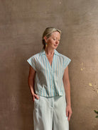 Mature woman wearing Dorada short sleeve Shirt from Trovata rendered in a fresh aqua and cream Stripe and crafted from  cotton poplin with v-neck, collar and consealed button front