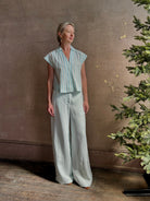 Mature woman wearing Dorada short sleeve Shirt from Trovata rendered in a fresh aqua and cream Stripe and crafted from  cotton poplin with v-neck, collar and consealed button front