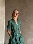 Mature woman wearing Trovata Martine button-up front cotton poplin green plaid maxi dress short sleeves and lightweight