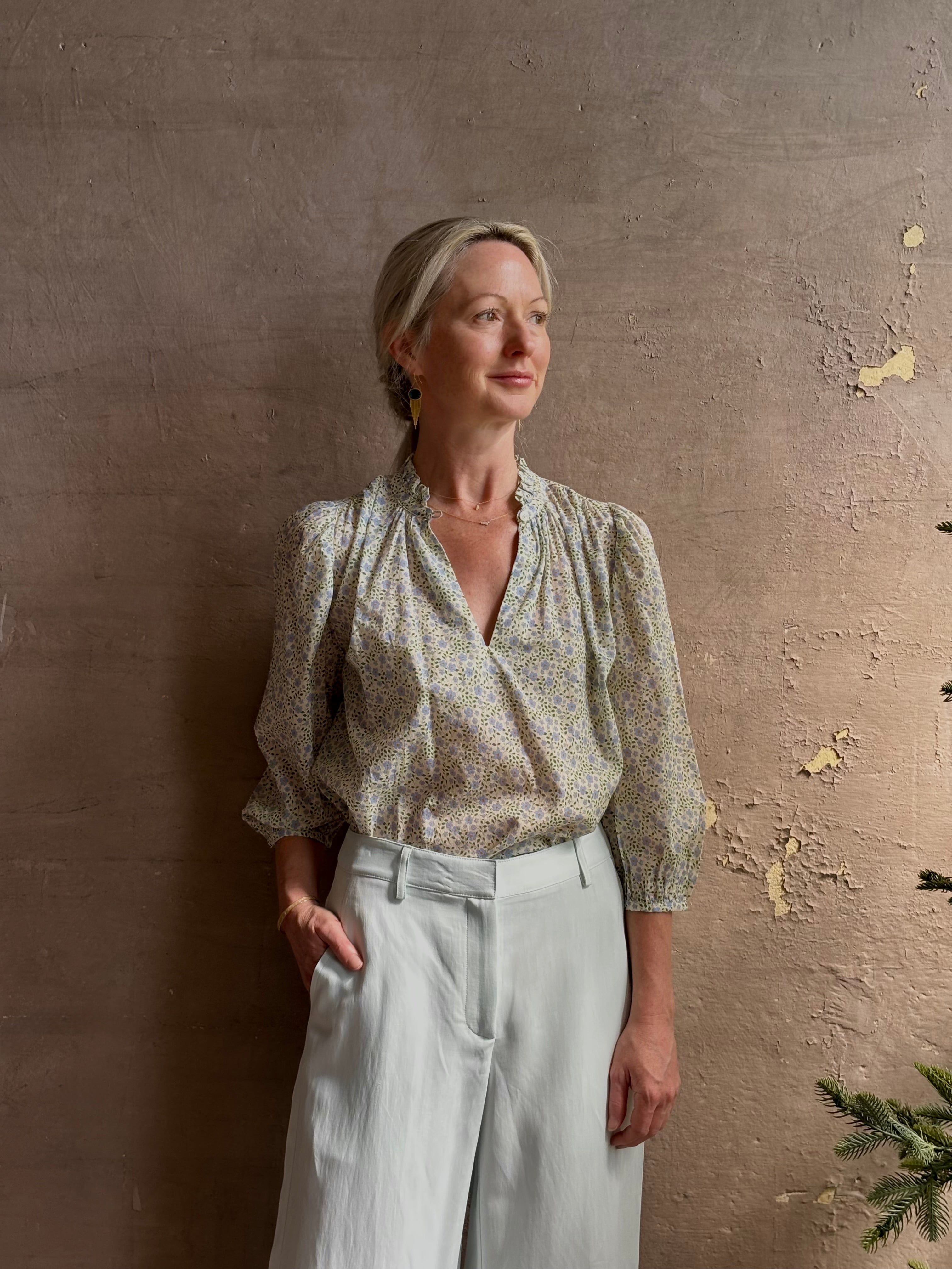 Mature woman wearing the Orly blouse from Trovata rendered in a charming coastal inspired floral print and crafted from cotton with three quarter sleeves and ruffle lined v-neck