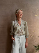 Mature woman wearing the Orly blouse from Trovata rendered in a charming coastal inspired floral print and crafted from cotton with three quarter sleeves and ruffle lined v-neck
