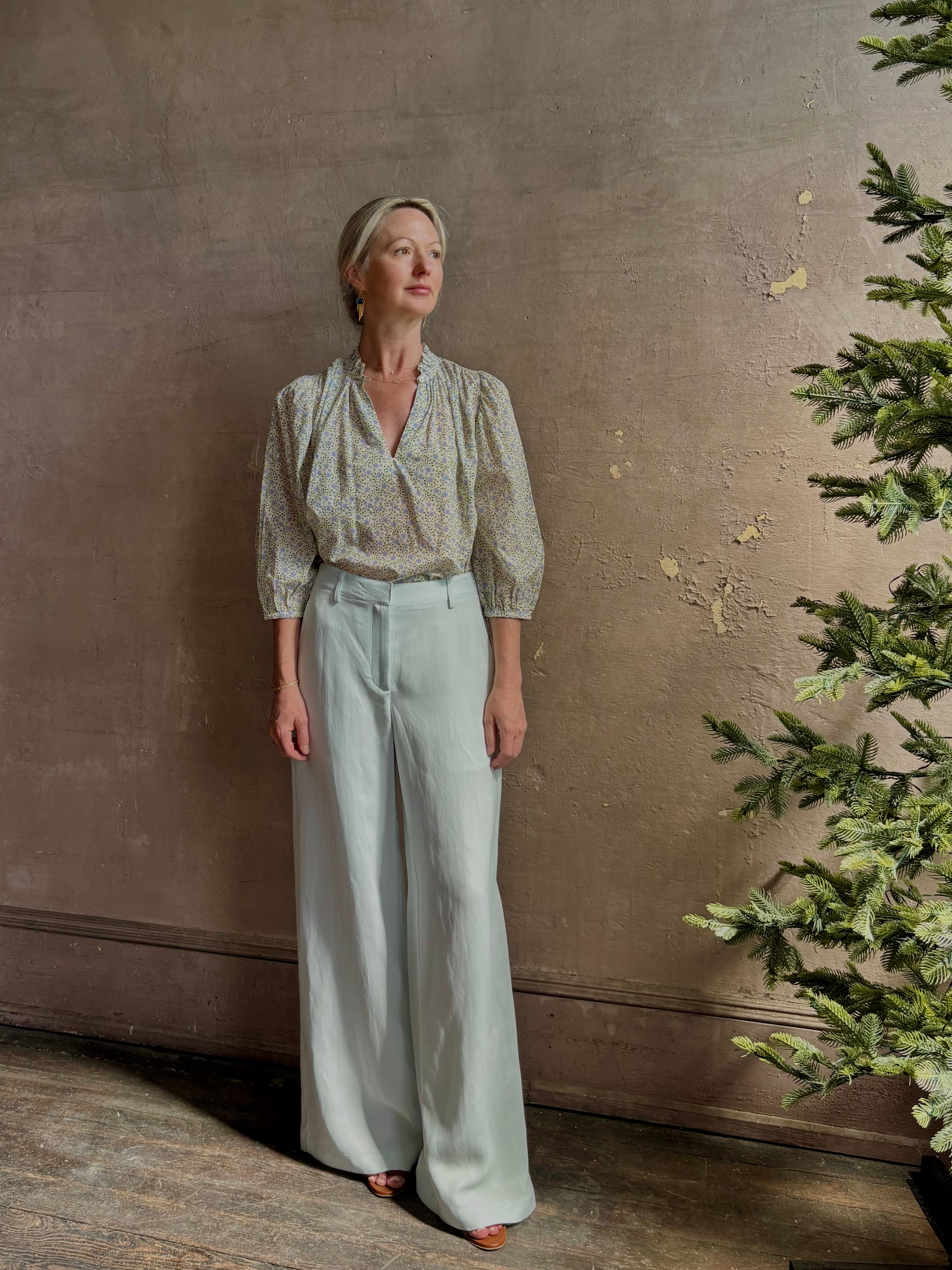 Mature woman wearing the Orly blouse from Trovata rendered in a charming coastal inspired floral print and crafted from cotton with three quarter sleeves and ruffle lined v-neck