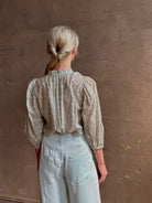 Mature woman wearing the Orly blouse from Trovata rendered in a charming coastal inspired floral print and crafted from cotton with three quarter sleeves and ruffle lined v-neck
