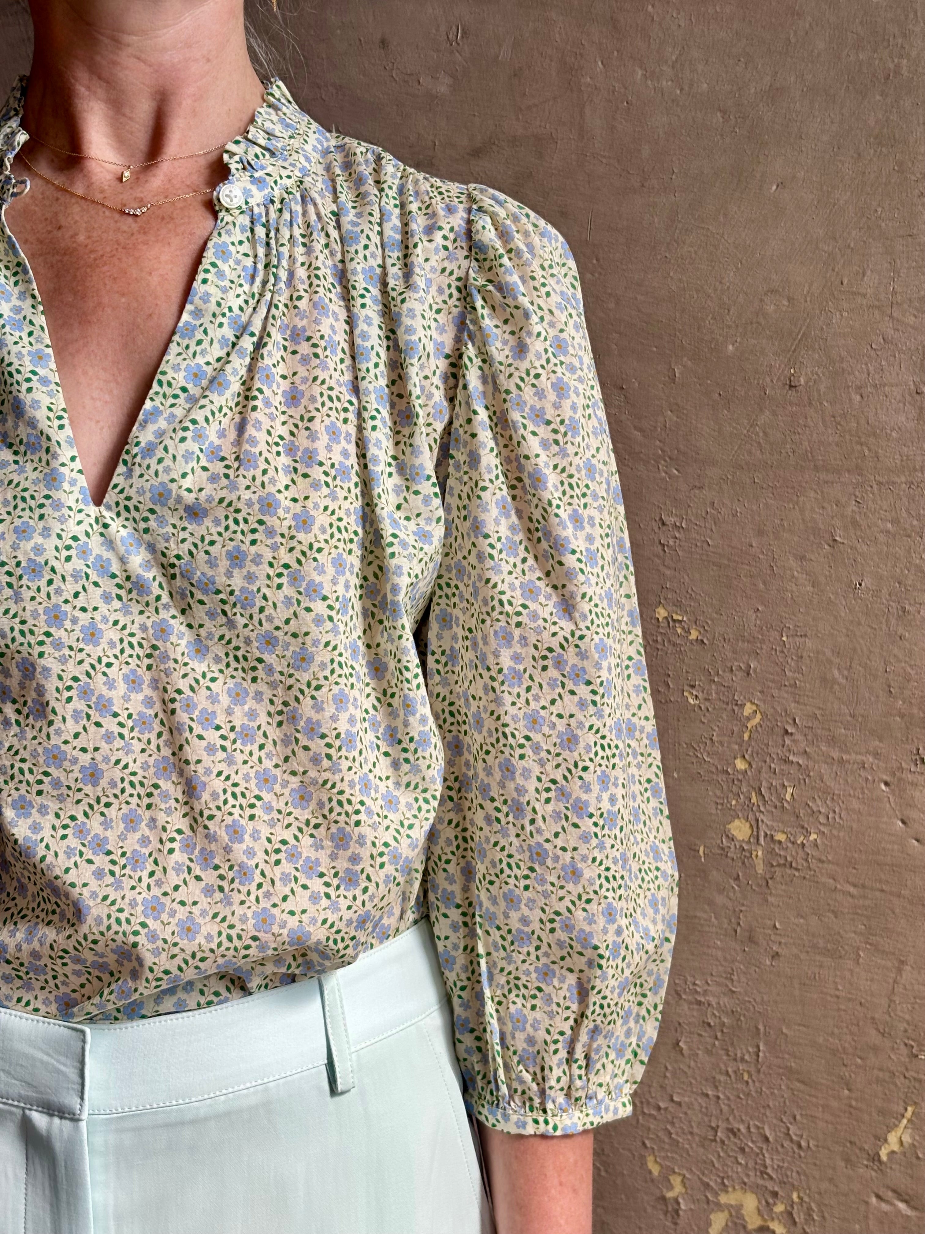 Mature woman wearing the Orly blouse from Trovata rendered in a charming coastal inspired floral print and crafted from cotton with three quarter sleeves and ruffle lined v-neck