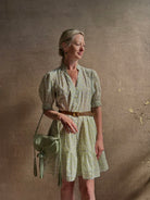 Mature woman wearing the short Phoebe Dress from Trovata rendered in a charming coastal inspired floral print and crafted from cotton with button front, ruffle lined short sleeves and v-neck