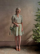 Mature woman wearing the short Phoebe Dress from Trovata rendered in a charming coastal inspired floral print and crafted from cotton with button front, ruffle lined short sleeves and v-neck
