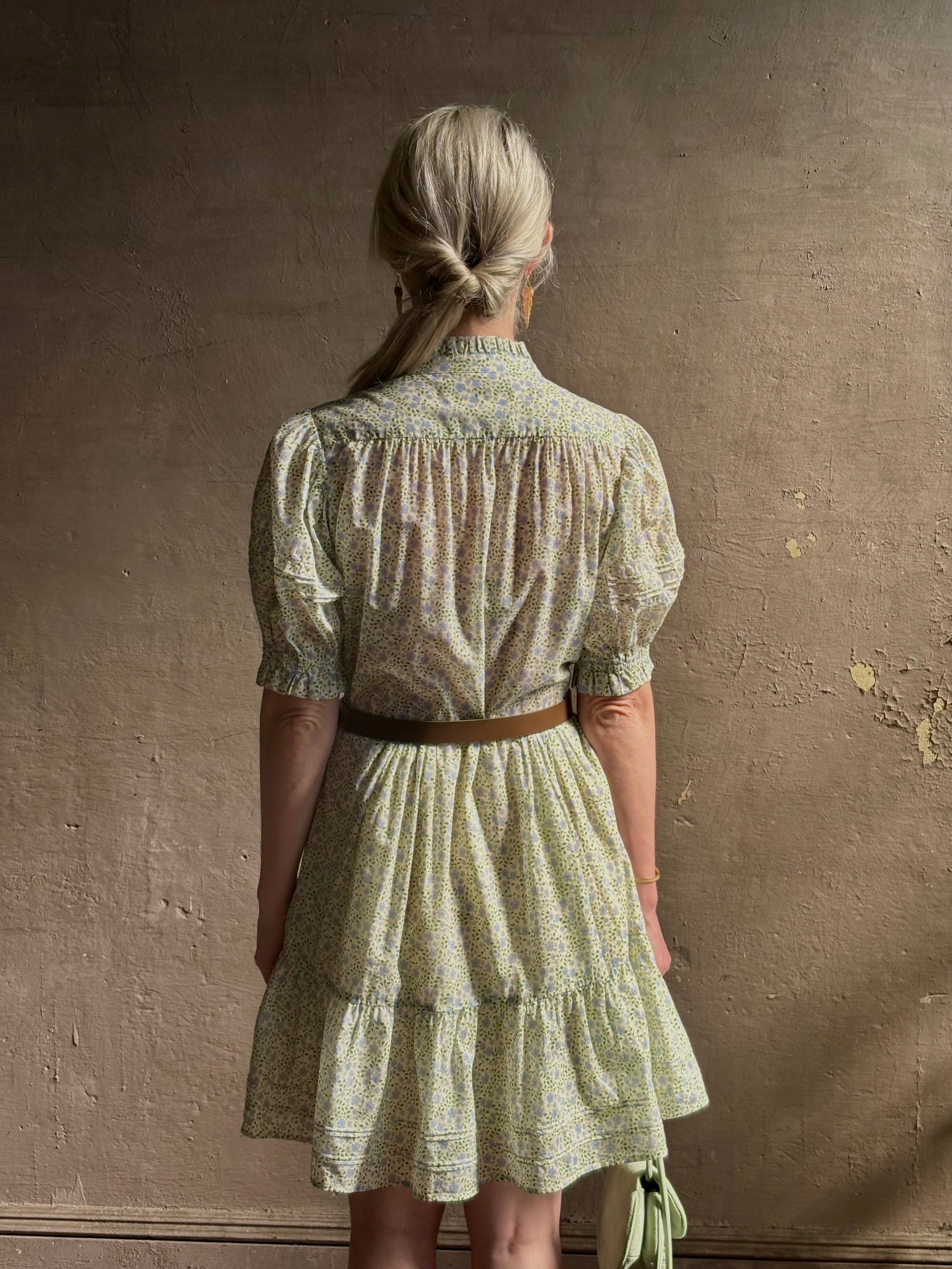 Mature woman wearing the short Phoebe Dress from Trovata rendered in a charming coastal inspired floral print and crafted from cotton with button front, ruffle lined short sleeves and v-neck