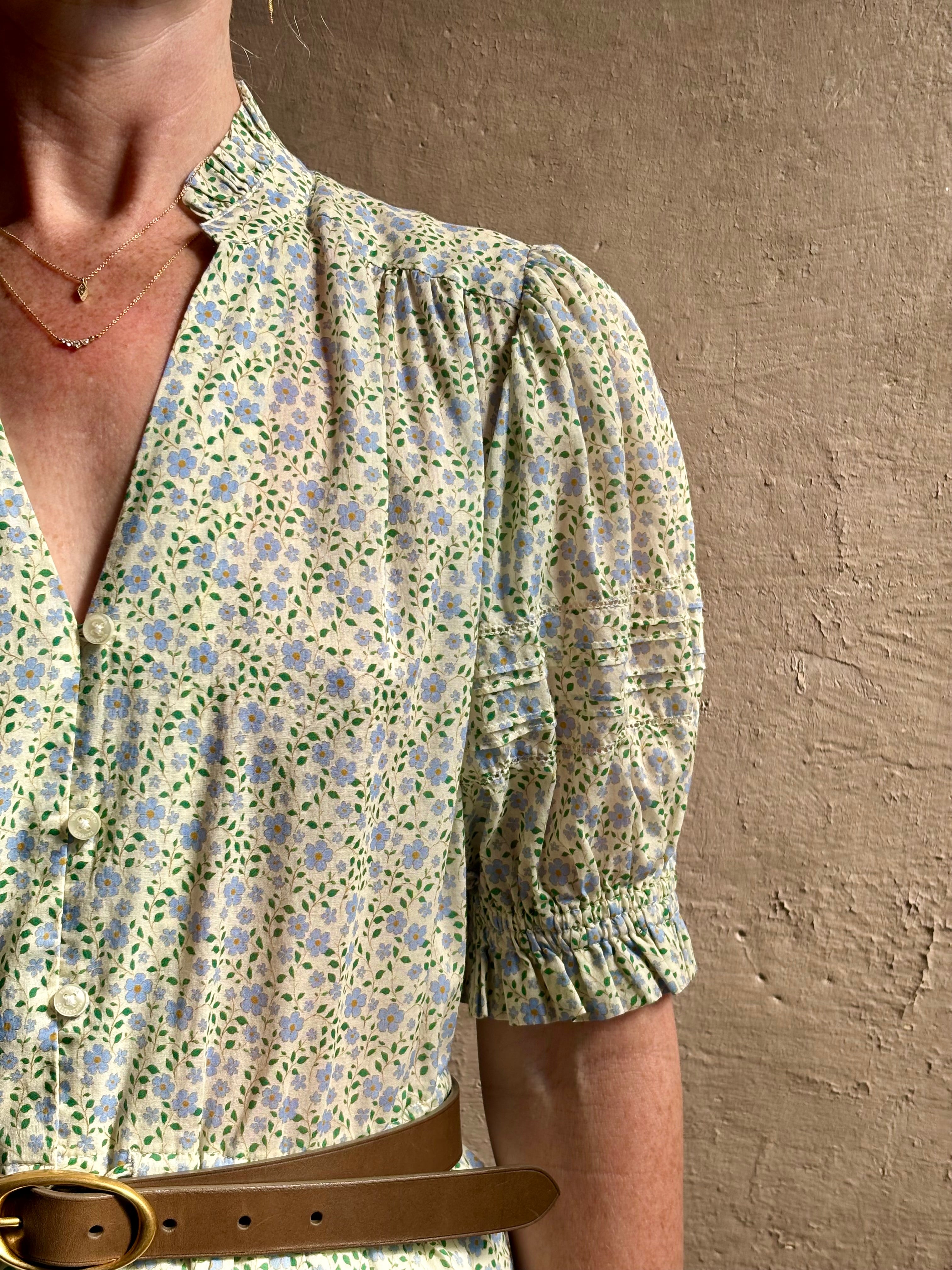 Mature woman wearing the short Phoebe Dress from Trovata rendered in a charming coastal inspired floral print and crafted from cotton with button front, ruffle lined short sleeves and v-neck