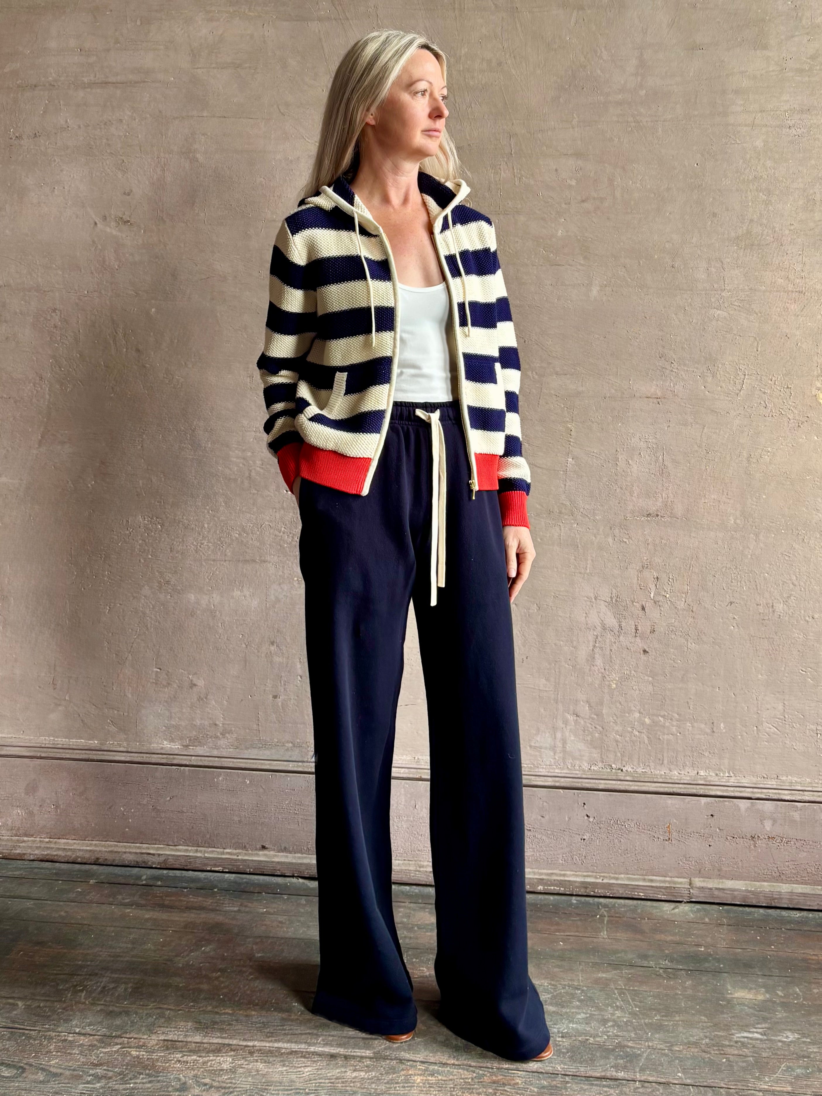 Mature woman wearing comfy cotton Rafa zip up hoodie by Trovata in a classic navy and white stripe with an elevated gold tone zipper.
