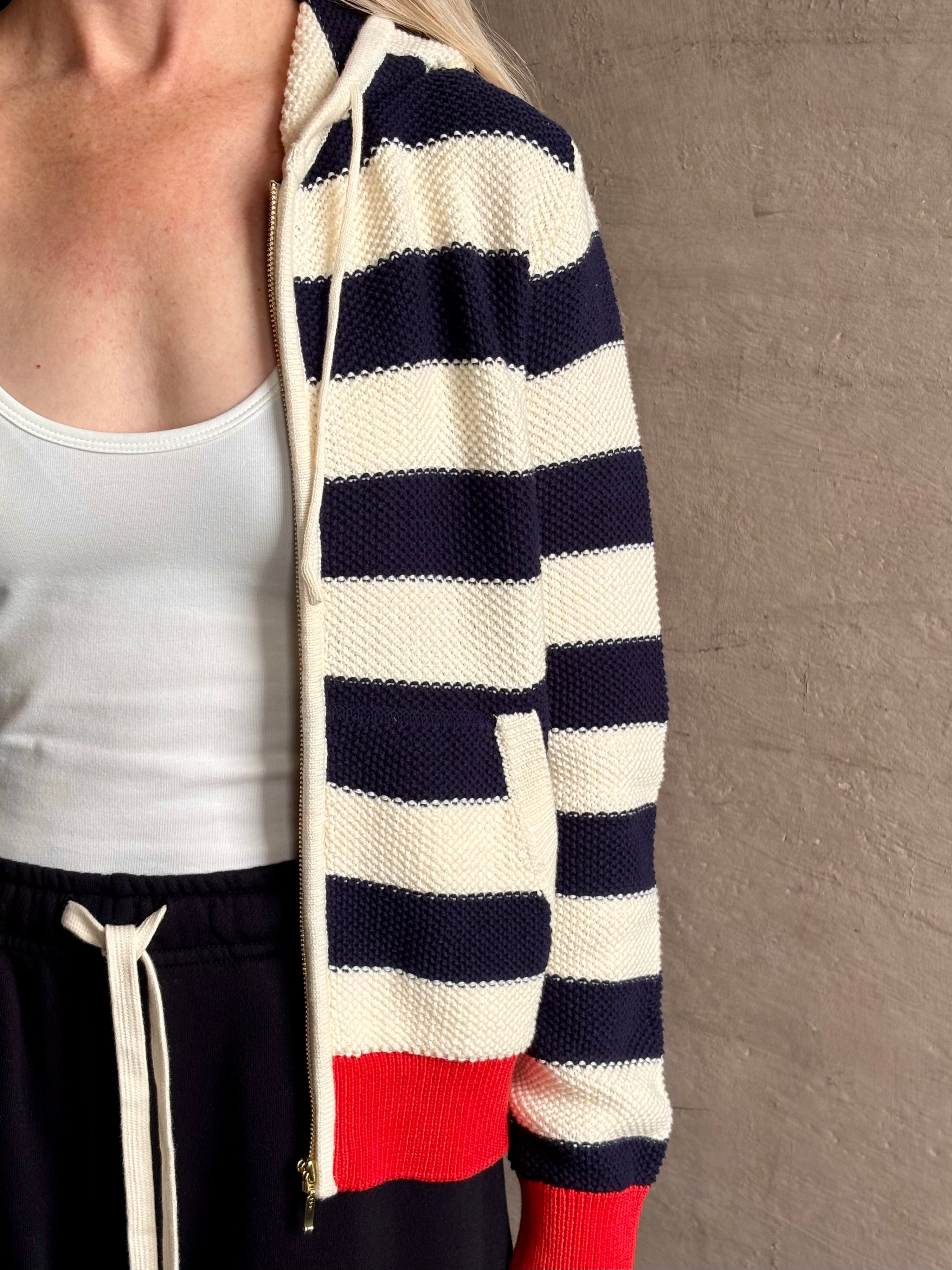 Mature woman wearing comfy cotton Rafa zip up hoodie by Trovata in a classic navy and white stripe with an elevated gold tone zipper.