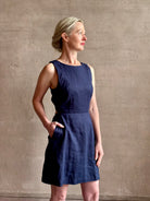 Woman wearing the effortless summer dress by Trovata Rosalie linen Dress in Navy Blue with A-line skirt and sophisticated bra friendly open back