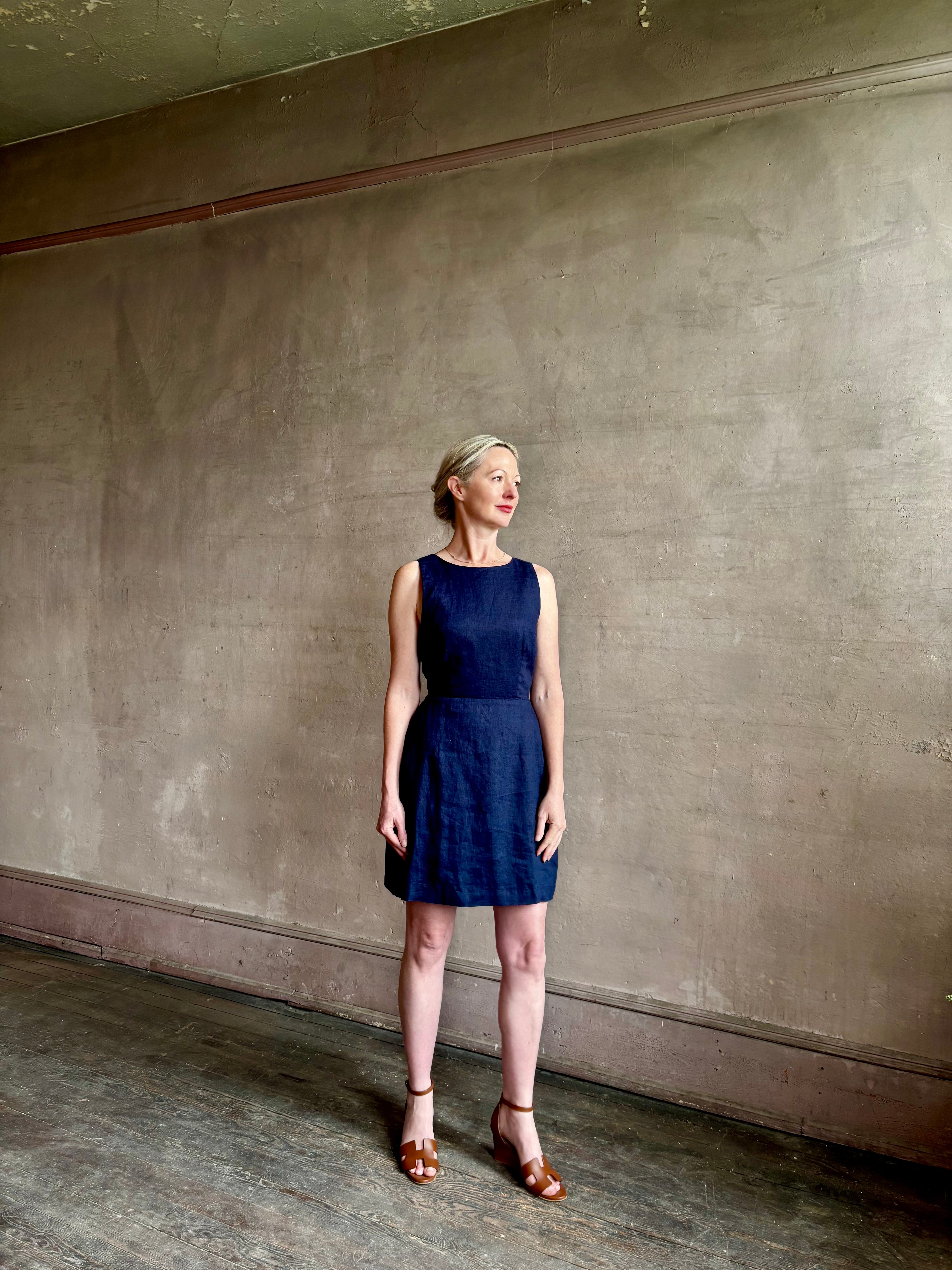 Woman wearing the effortless summer dress by Trovata Rosalie linen Dress in Navy Blue with A-line skirt and sophisticated bra friendly open back