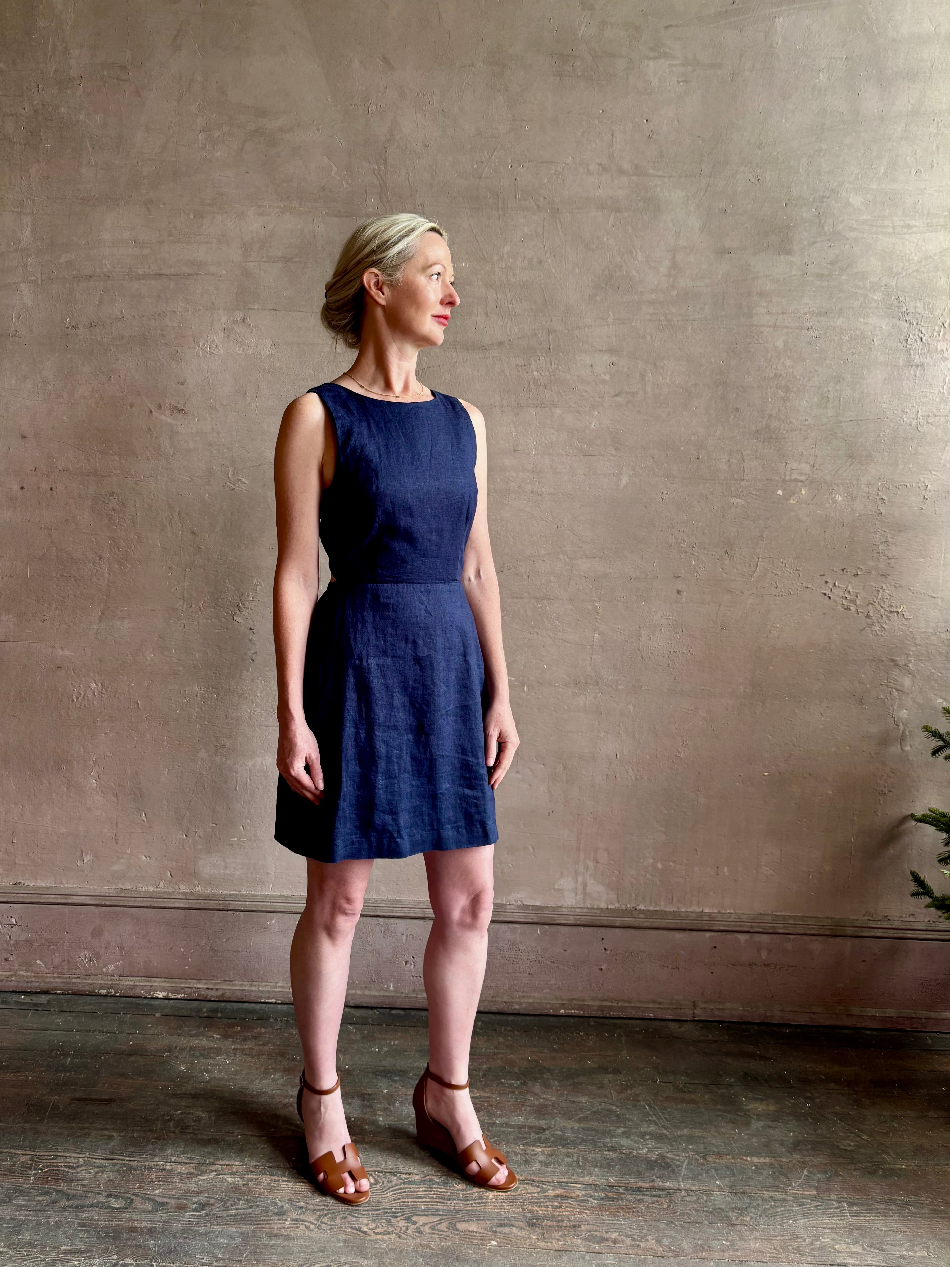 Woman wearing the effortless summer dress by Trovata Rosalie linen Dress in Navy Blue with A-line skirt and sophisticated bra friendly open back
