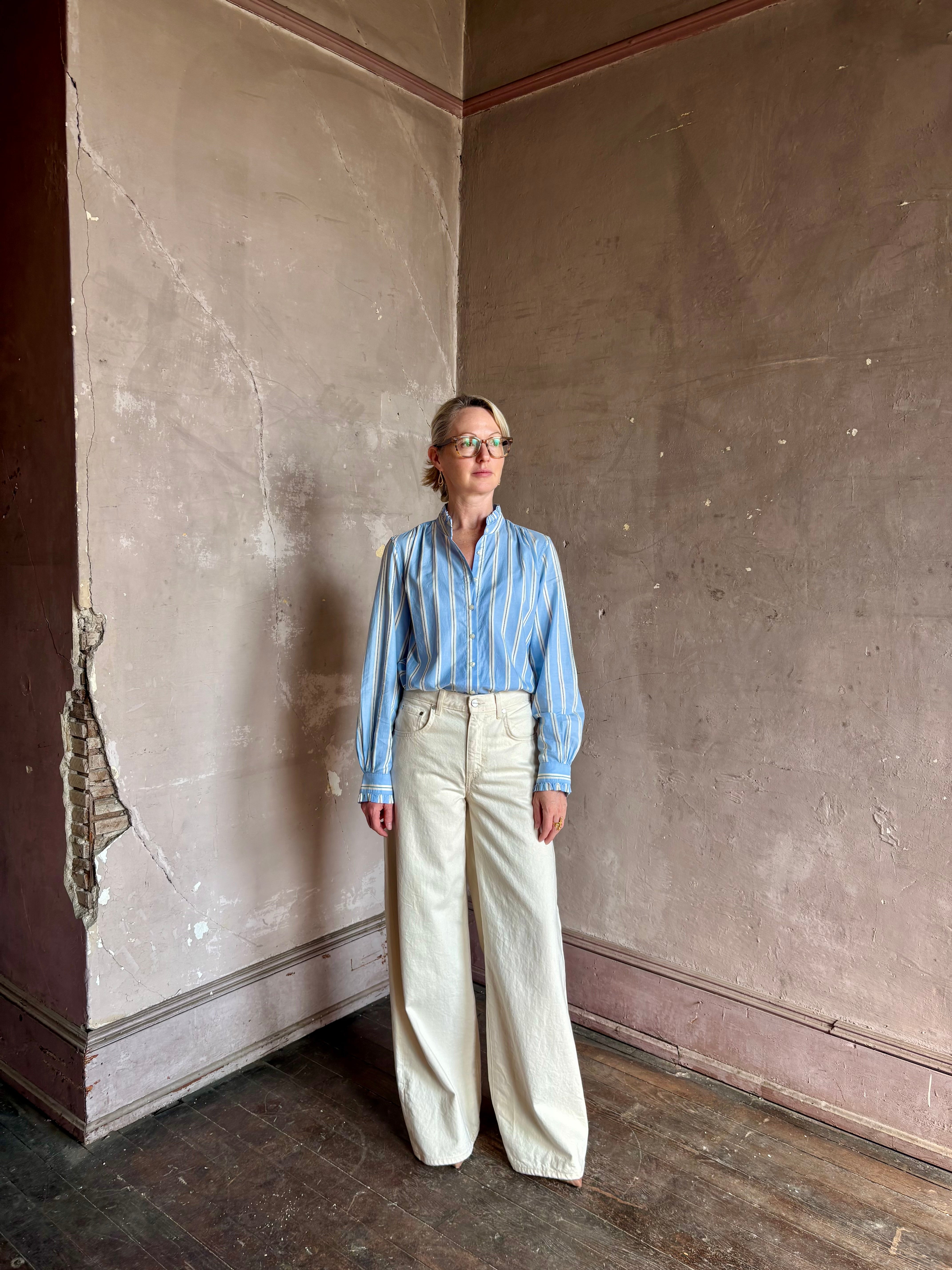 Mature woman wearing blue and cream vertically striped long-sleeve cotton Trovata Rumi button front shirt
