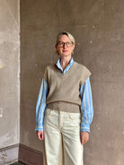 Mature woman wearing beige knit sweater vest over a blue and white striped button-down Trovata Rumi shirt
