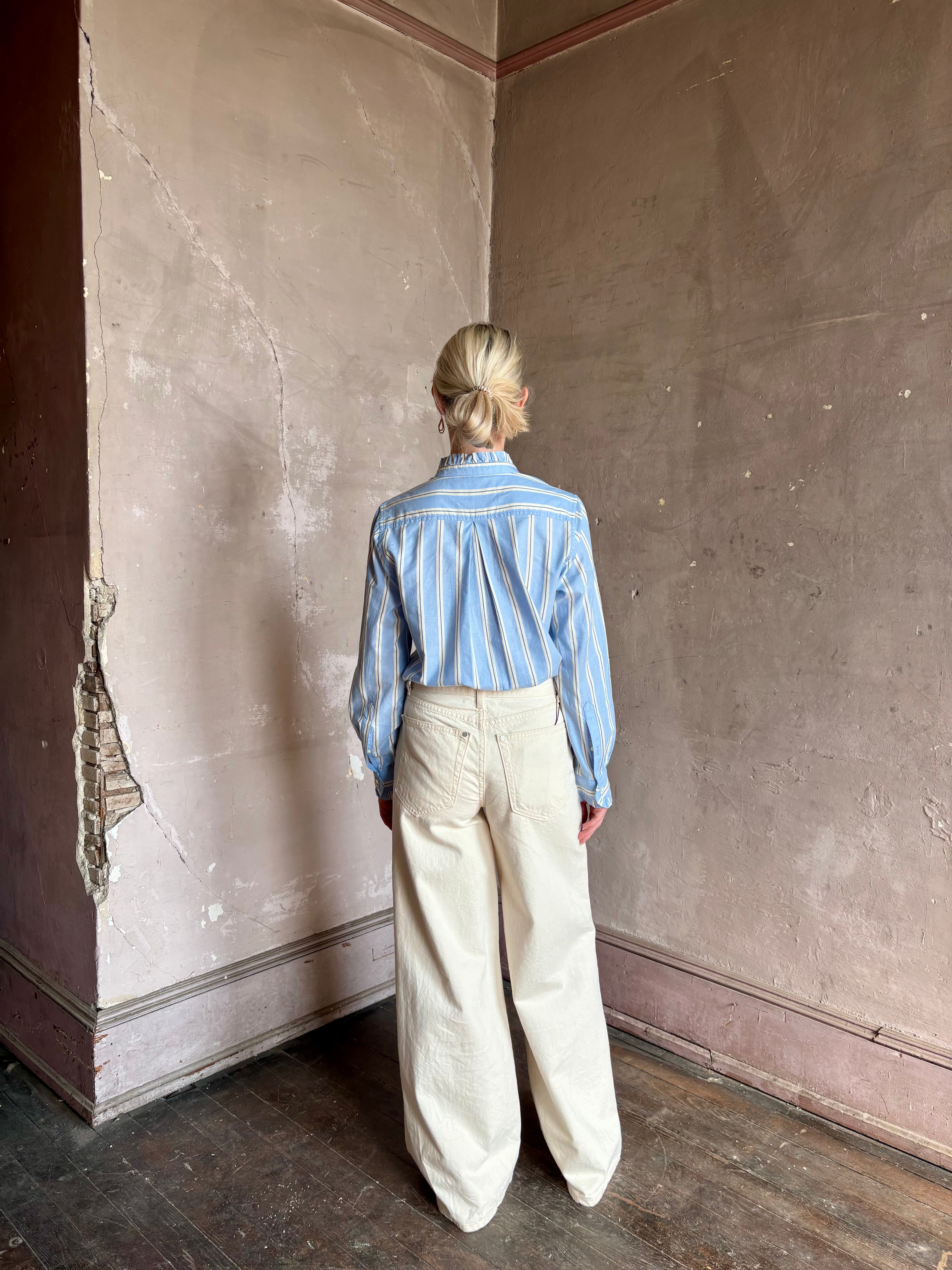 Mature woman wearing blue and cream vertically striped long-sleeve cotton Trovata Rumi shirt ruffle lined cuffs